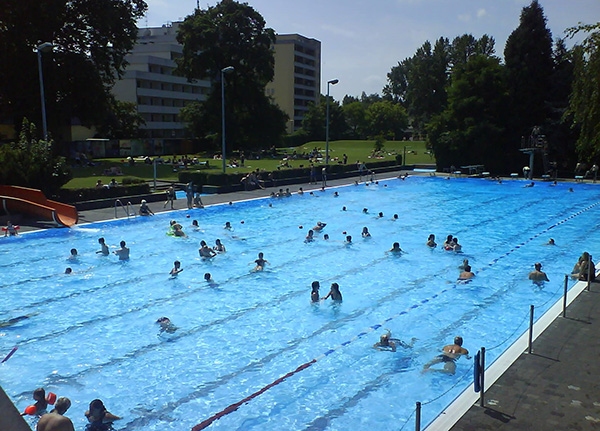 Schwimmbecken im Nordbad mit acht Bahnen. Viele Menschen schwimmen im Becken.