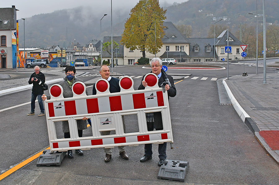 Edeltrud Bayer (Landesbetrieb Mobilität), Ortsvorsteher Marc Borkam und Beigeordneter Andreas Ludwig (v. l.) entfernen die letzte Barriere am neuen Römerbrückenkreisel.